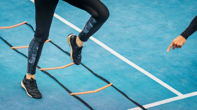 Jonge vrouw oefent met behulp van Agility Ladder in samenwerking met een fitnesscoach