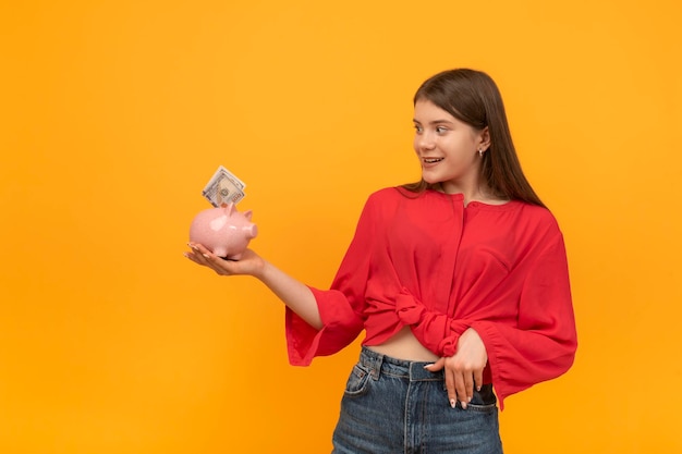 Jonge vrouw of meisje houdt spaarvarken met geld in handen en kijkt er verbaasd naar financieel geletterdheid concept