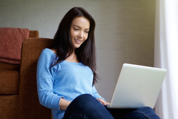 Jonge vrouw om thuis te zitten met behulp van laptop