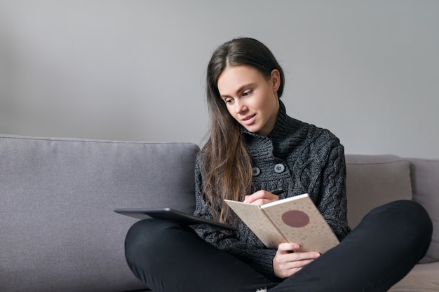 Jonge vrouw om thuis te zitten op de bank met gadgets