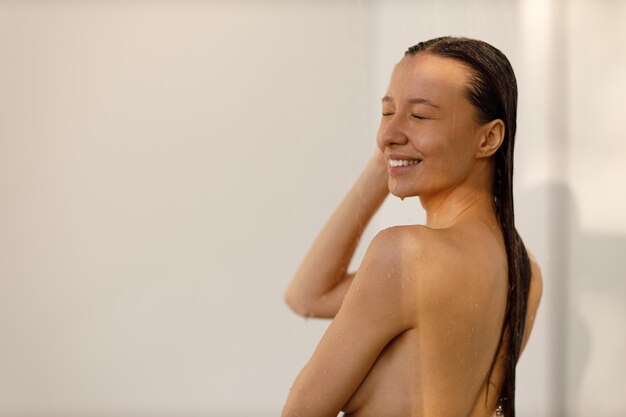 Jonge vrouw onder de straaltjes water in plezierdouche Mooi meisje onder de nevel van water Nat blij gezicht