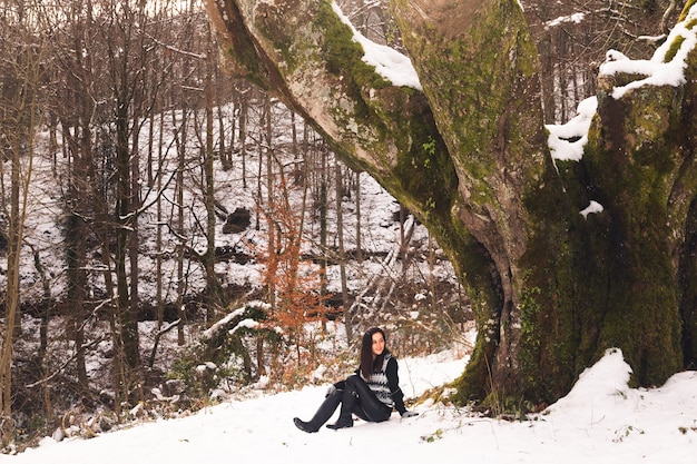 Jonge vrouw onder een enorme beuk in het bos van Baskenland.