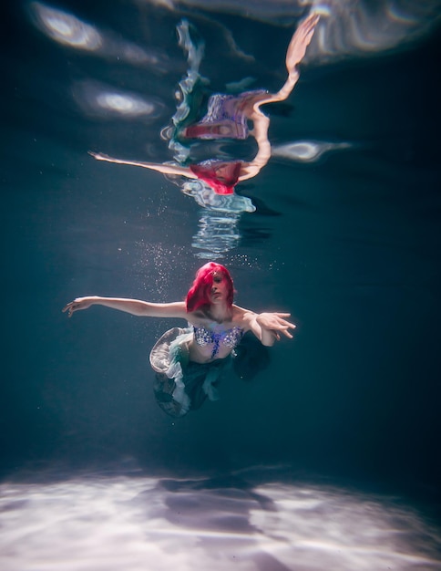 Jonge vrouw onder water in een mooie jurk onderwater fotograferen