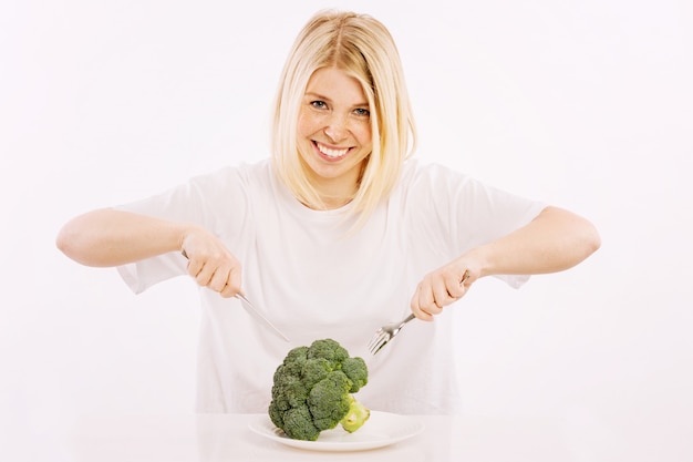 Jonge vrouw ongeveer om broccoli van een plaat te eten
