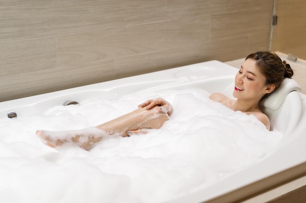 Jonge vrouw ontspannen en neemt bubbelbad in bad met schuim