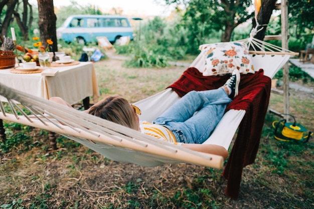 Jonge vrouw ontspannen in de hangmat buiten, in de achtertuin. Genieten van de zomer