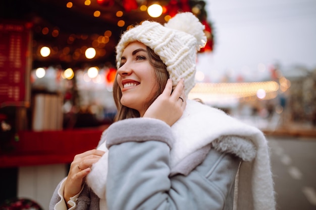 Foto jonge vrouw ontspannen koffie drinken in feestelijke kerstmarkt wintervakantie lichten rond