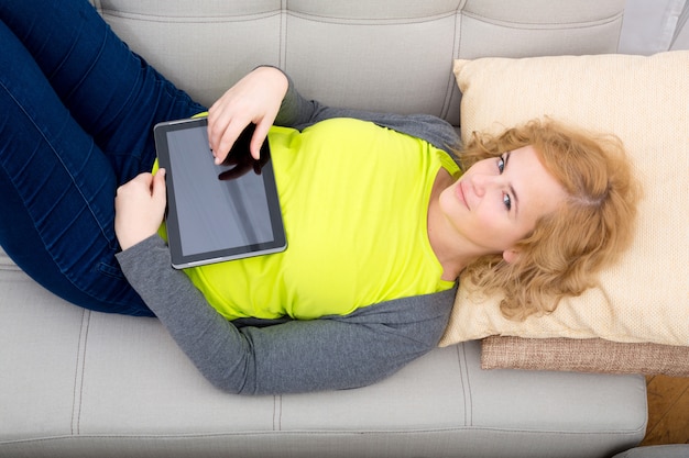 Jonge vrouw ontspannen met een tablet-pc op de Bank