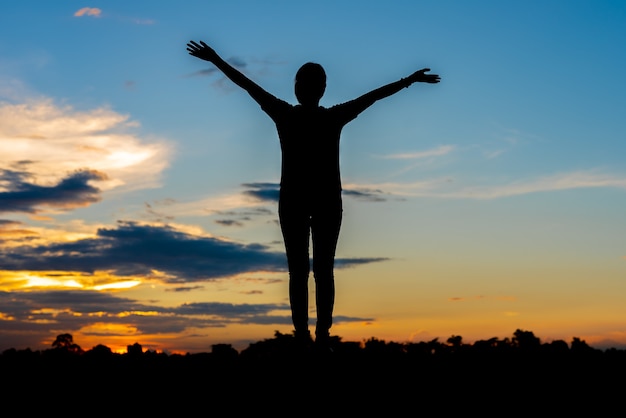 Jonge vrouw ontspannen whit avondrood buiten.