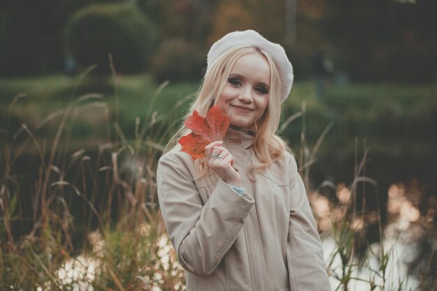 Jonge vrouw ontspant zich op het meer met een rood herfstblad.