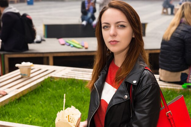 Jonge vrouw op bank met meeneem voedselcontainer