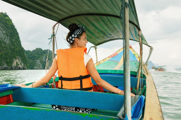 Jonge vrouw op de longtailboot tijdens haar vakanties in Thailand