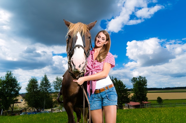 Jonge vrouw op de weide met paard