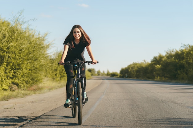 Jonge vrouw op een fiets die op de weg berijdt