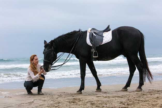 Jonge vrouw op een paard op het strand