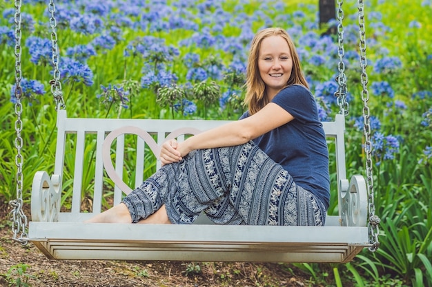 Jonge vrouw op een schommel in een bloementuin