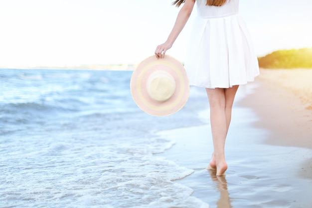 Jonge vrouw op een strand met een witte hoed. Benen close-up.