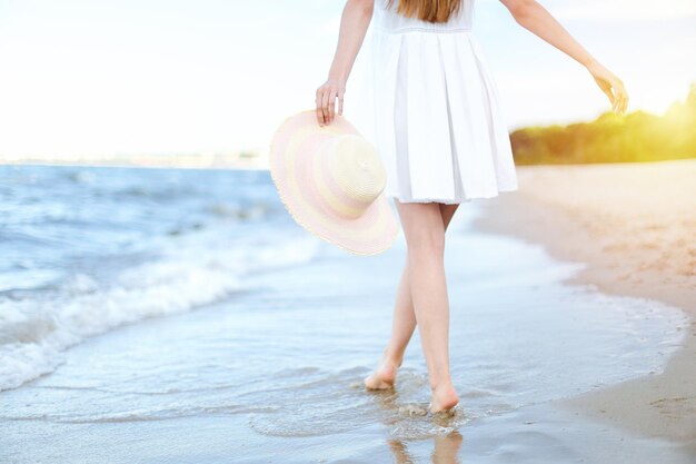 Jonge vrouw op een strand met een witte hoed. Benen close-up