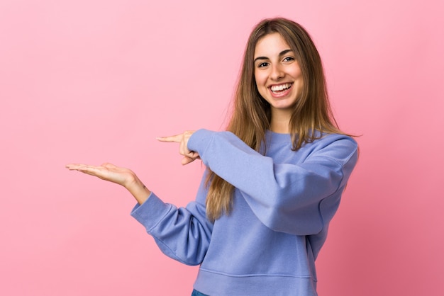 Jonge vrouw op geïsoleerde roze holding copyspace denkbeeldig op de palm om een advertentie op te nemen