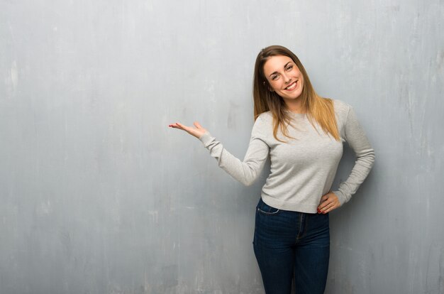 Jonge vrouw op geweven muur die copyspace denkbeeldig op de palm houdt om een advertentie in te voegen