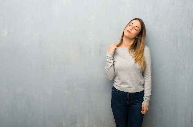 Jonge vrouw op geweven muur met vermoeide en zieke uitdrukking