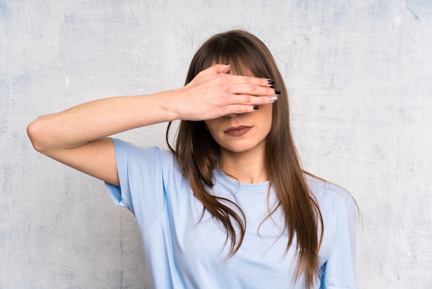 Jonge vrouw op grungeachtergrond die ogen behandelen door handen