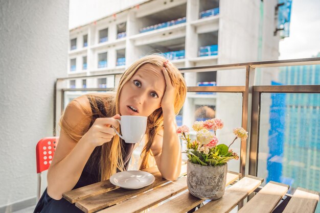 Jonge vrouw op het balkon geïrriteerd door de bouwwerkzaamheden buiten Geluidsconcept Luchtvervuiling door bouwstof