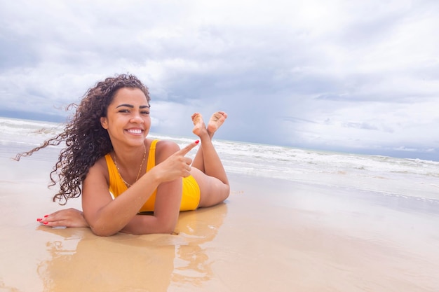 Jonge vrouw op het strand Afro-vrouw zittend op het strandzand op een mooie zomerdag