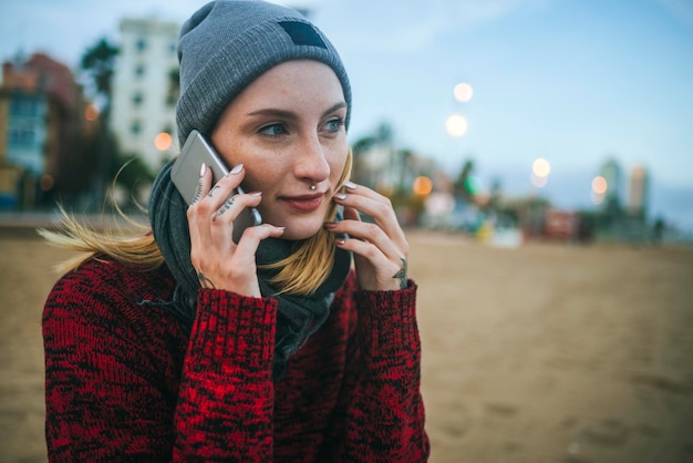 Jonge vrouw op het strand in de winter op mobiele telefoon