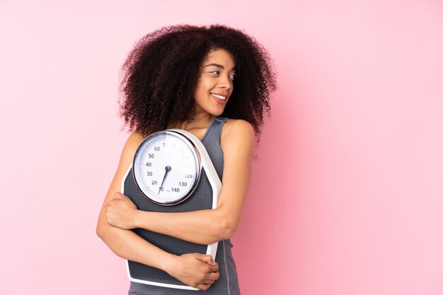 Jonge vrouw op roze met wegende machine en het kijken kant