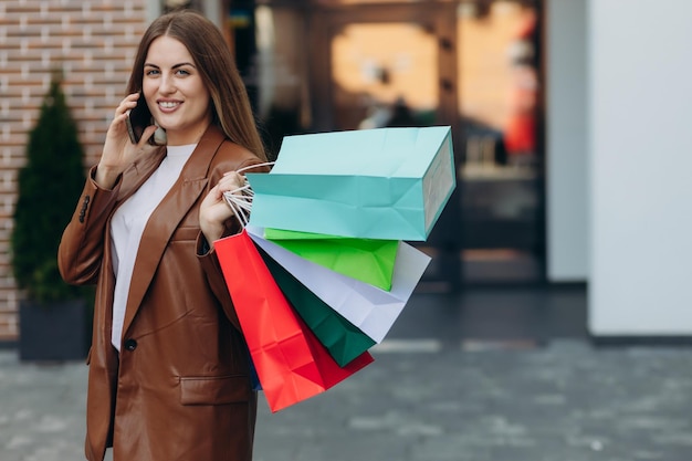 Jonge vrouw op straat met gekleurde tassen praten op een mobiele telefoon