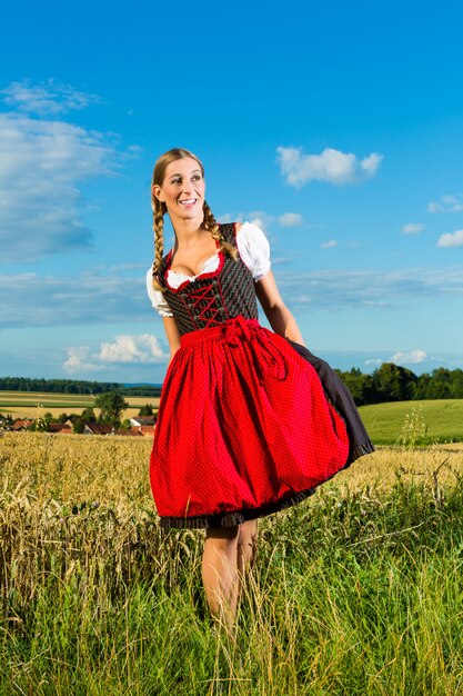 Jonge vrouw op weide die dirndl draagt