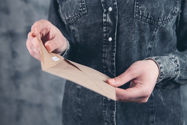 Jonge vrouw opent een postenvelop