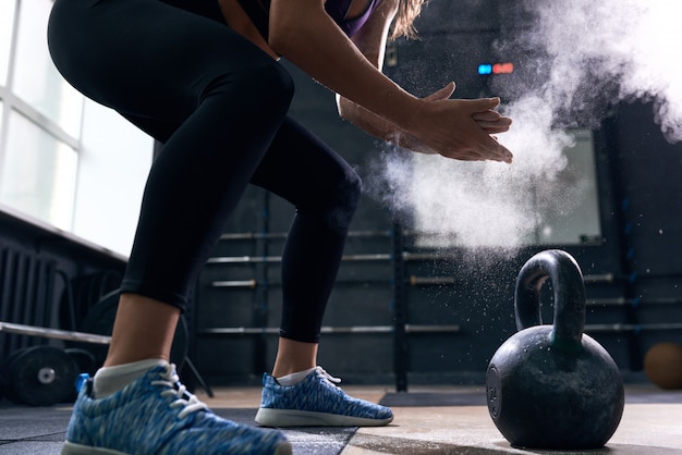 Jonge vrouw opheffen kettlebells in crossfit gym