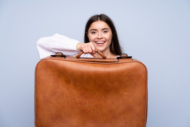 Jonge vrouw over geïsoleerd blauw die een uitstekende aktentas houdt