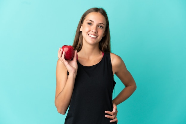 Jonge vrouw over geïsoleerde blauwe achtergrond met een appel en happy