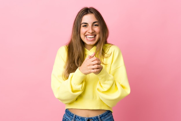 Jonge vrouw over geïsoleerde roze muur lachen