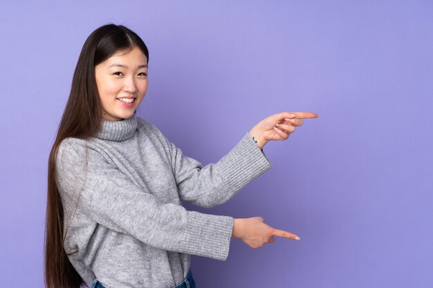 Jonge vrouw over wijzende vinger aan de zijkant en het presenteren van een product