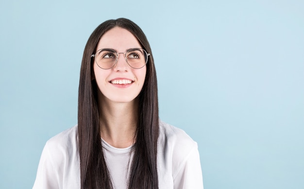 Jonge vrouw poseren geïsoleerd op blauwe muur achtergrond, kijken naar de copyspace in de rechterbovenhoek