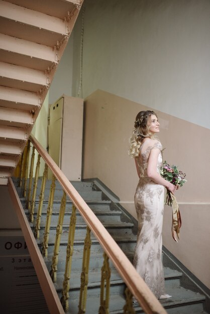 Jonge vrouw poseren in een lichte lange kanten jurk met een boeket bloemen in haar handen