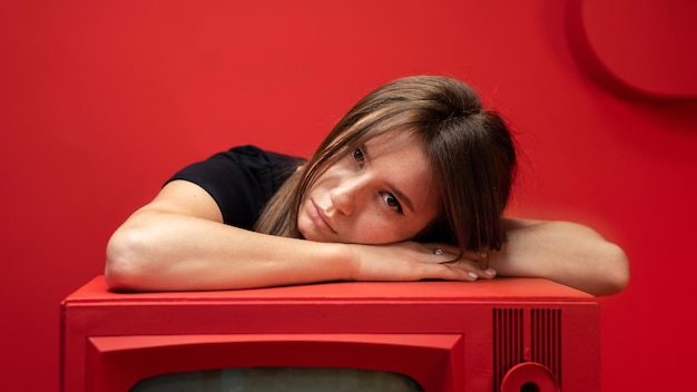 Jonge vrouw poseren in een studio met rode muren en meubels Oude vintage TV