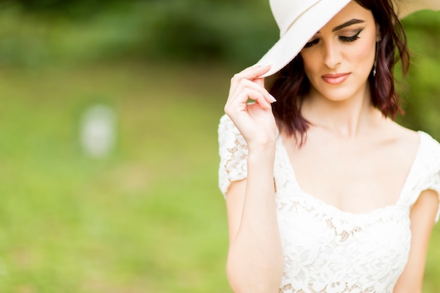 Jonge vrouw poseren in een witte jurk met een hoed