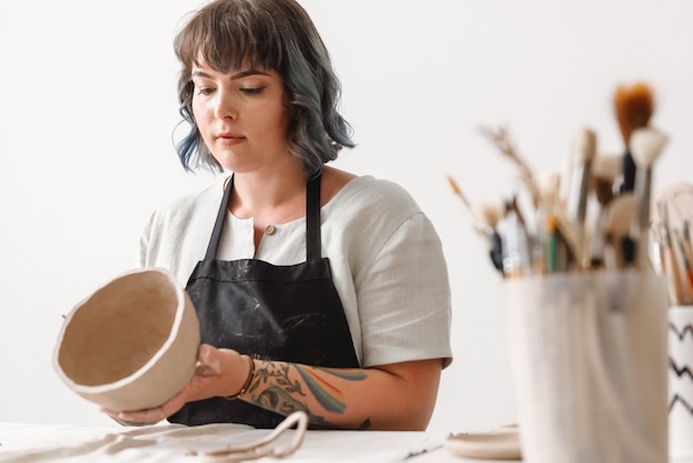 Foto jonge vrouw pottenbakker gerechten aarden pot maken