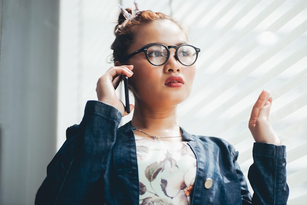 Jonge vrouw praat op een smartphone bij het raam.