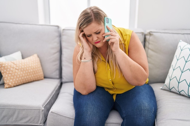 Jonge vrouw praten op de smartphone met een bezorgde uitdrukking thuis