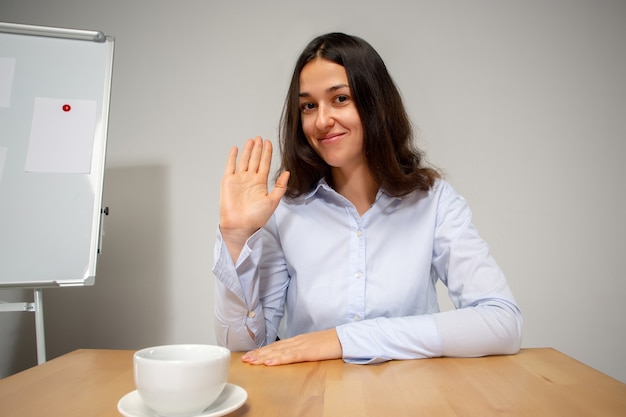 Jonge vrouw praten, werken tijdens videoconferentie met collega's op kantoor aan huis