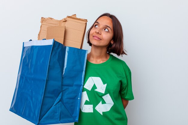 Jonge vrouw recycling karton geïsoleerd op een witte muur dromen van het bereiken van doelen en doeleinden