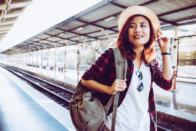 Jonge vrouw reiziger dragen rugzak wachten spoorweg op treinstation, zomervakantie en reis concept