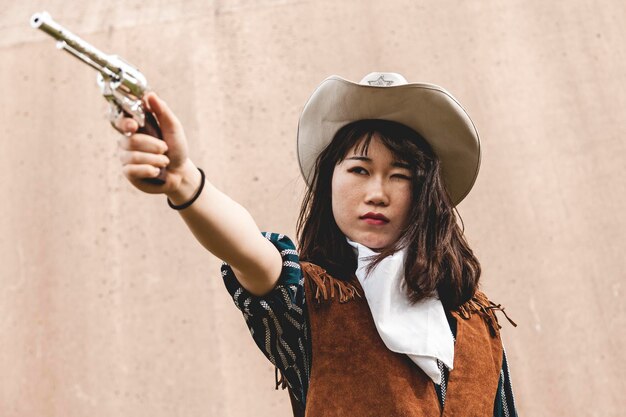 Foto jonge vrouw richt een pistool terwijl ze tegen de muur staat