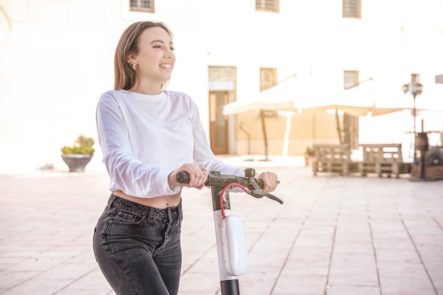 Foto jonge vrouw rijden op een elektrische scooter dorp achtergrond